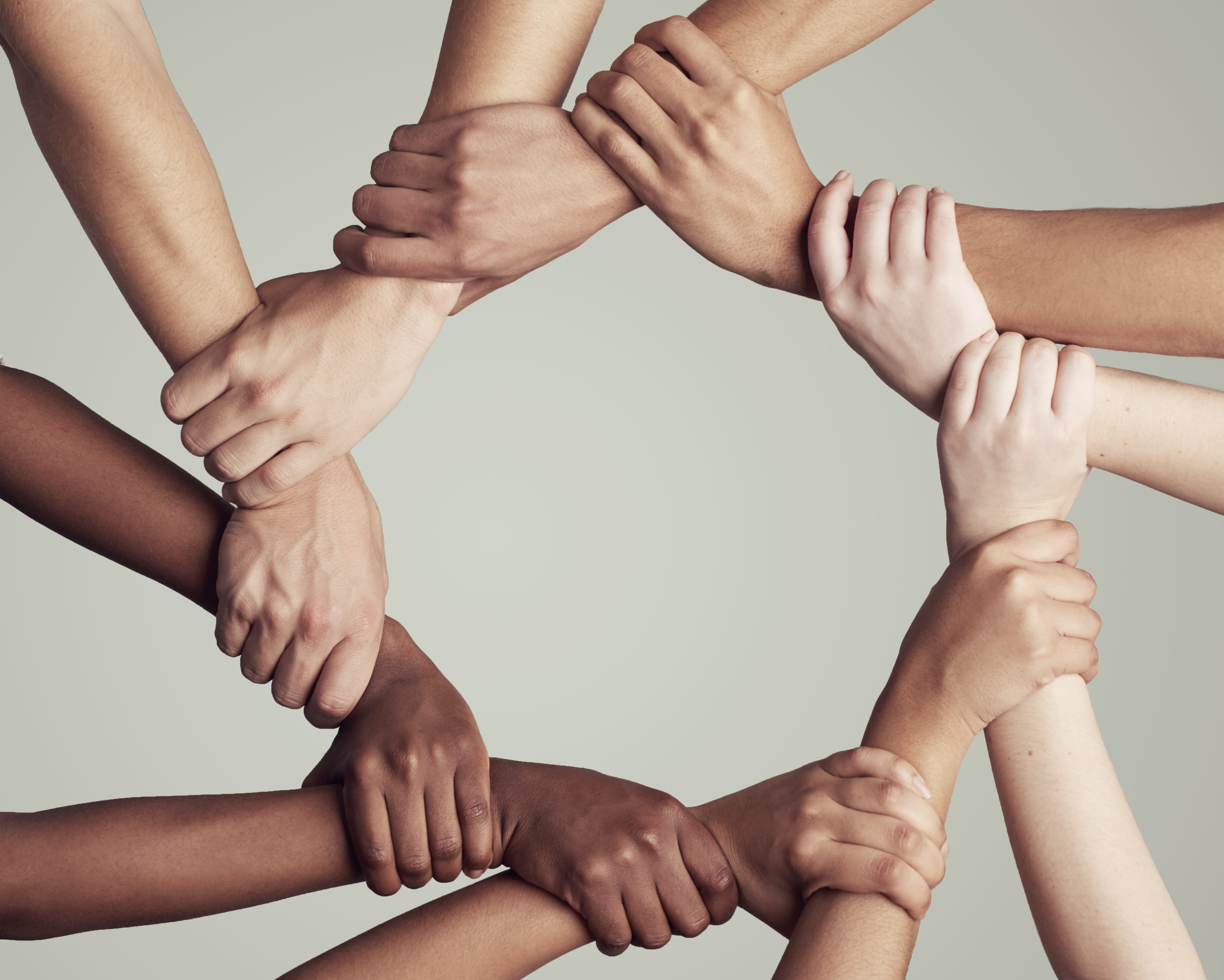 Cropped shot of a diverse group of unidentifiable people holding hands in a circle